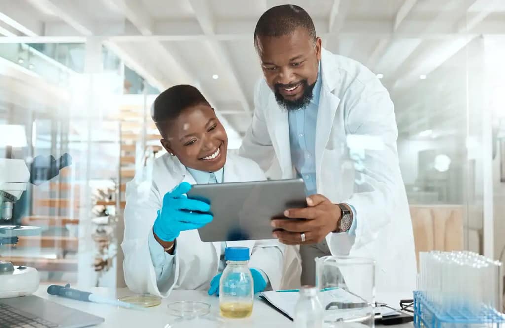 Scientists smiling while reviewing data on a tablet, representing individual solutions.